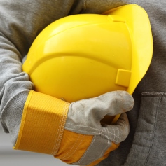 Person in work gloves holding a yellow hard hat