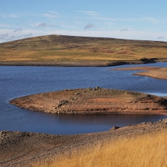 river surrounded by arid land and hills