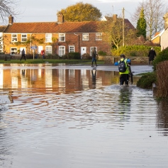 people walking through flood water in a village 