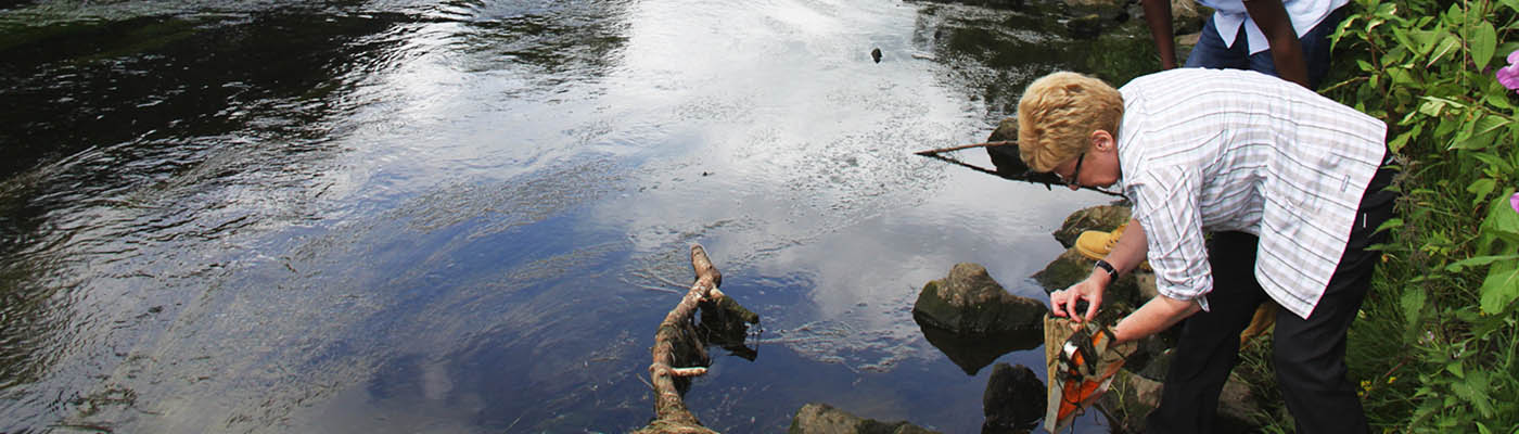 A woman inspects a sample she's just collected from a river.