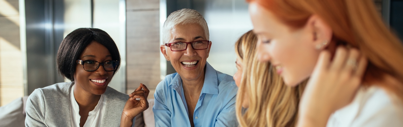 Group of business women sat smiling and laughing 