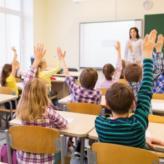 Children putting their hand up in class